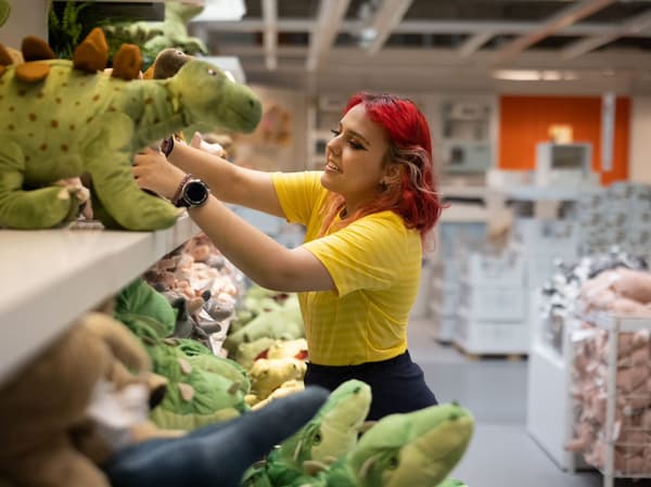 Eine IKEA Auszubildende räumt Kuscheltiere in der Kinderabteilung in die Regale.