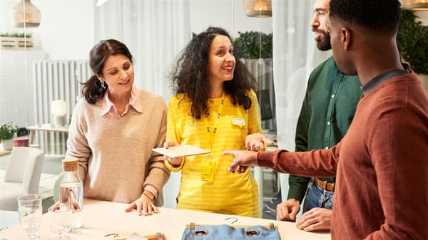 Eine IKEA Mitarbeiterin zeigt Kunden verschiedene Muster an einem Tisch