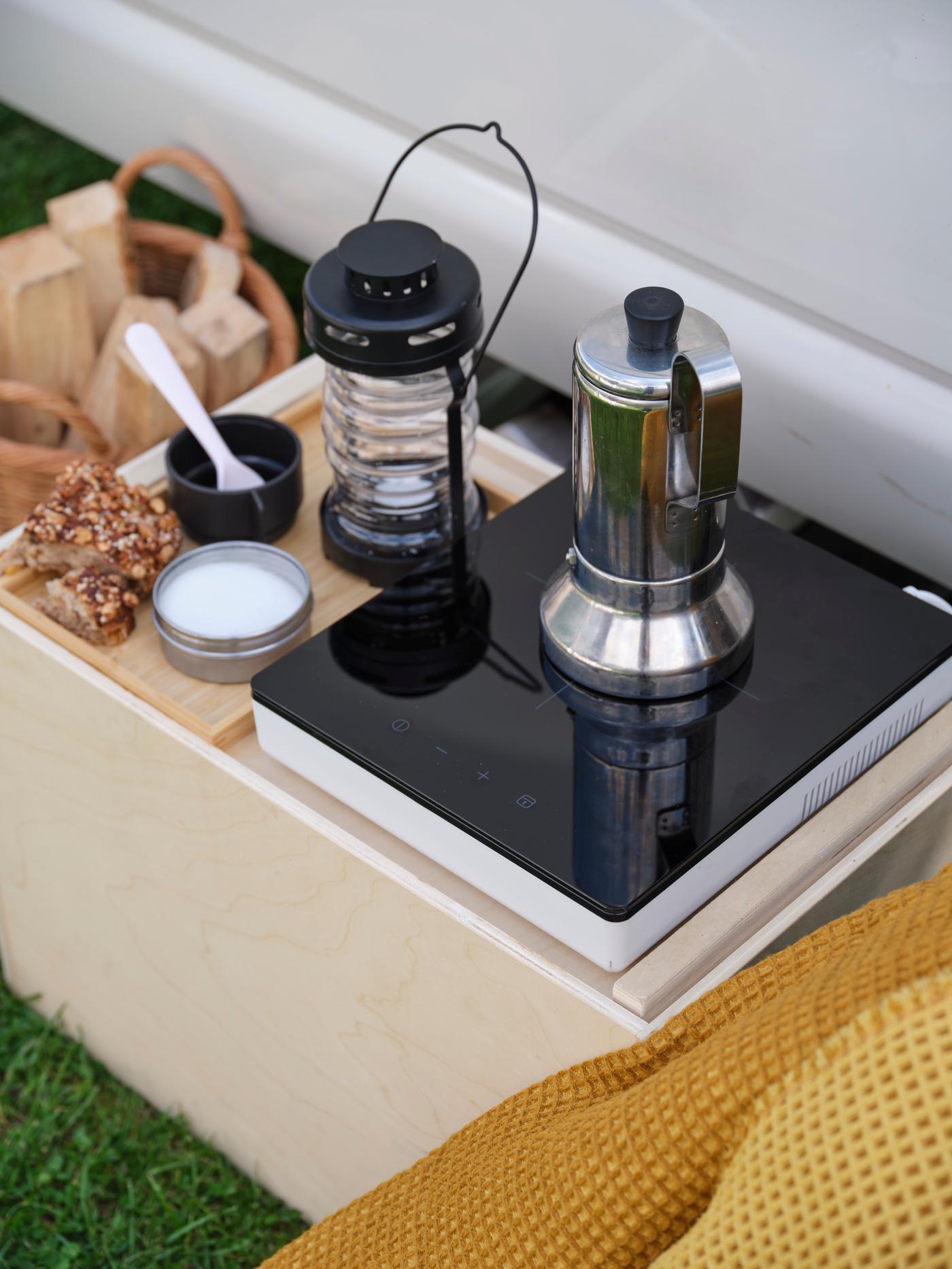 Eine Kaffeemaschine, die auf der tragbaren Induktionsanlage von TILLREDA steht und daneben eine Solarlaterne.