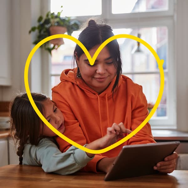eine Mutter und Ihre Tochter zuhause beim Esstisch am Tablett, darüber eine IKEA Abbildung eines Herzes