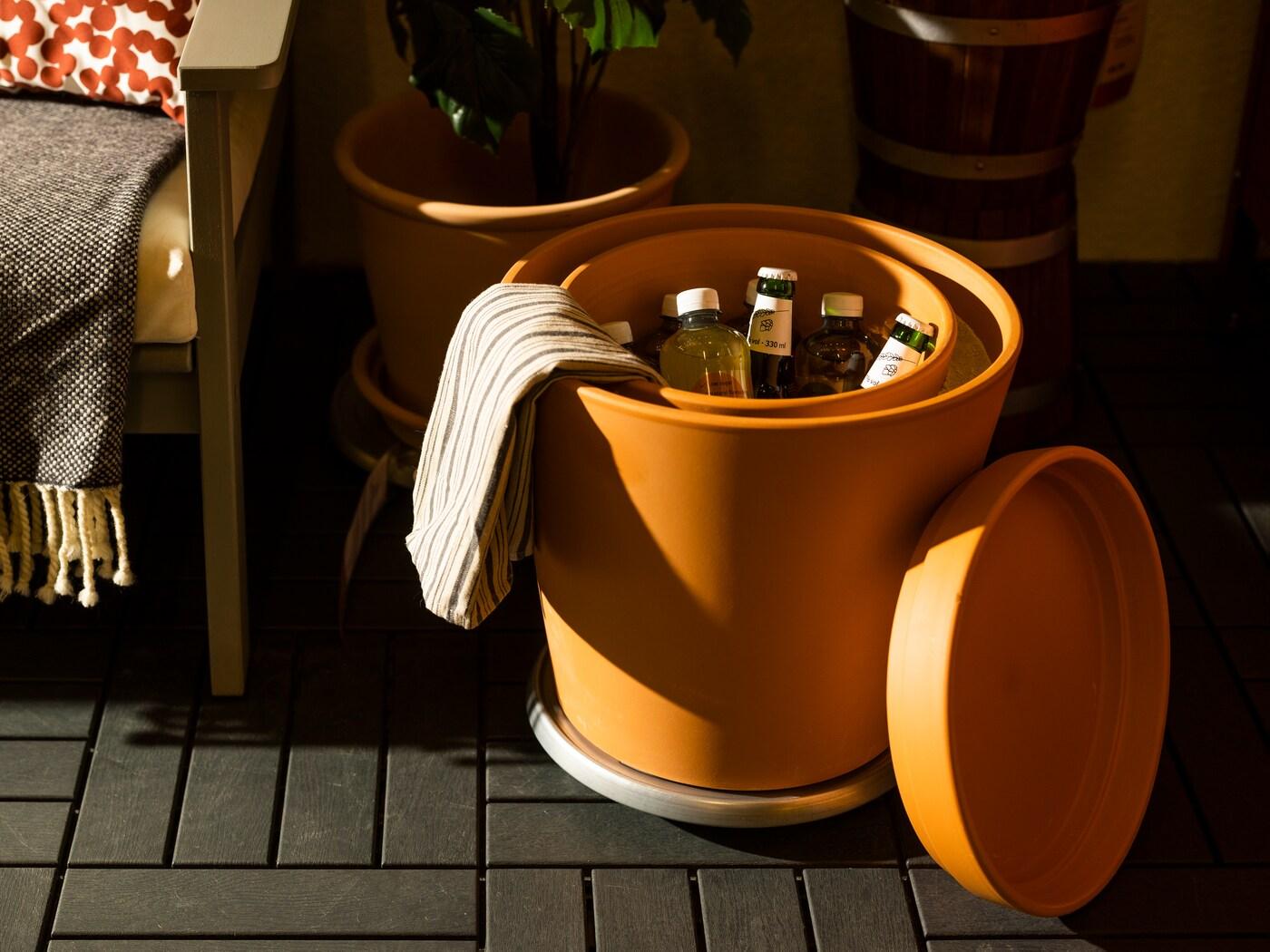 Eine orangene Box steht auf dem Boden und kühlt Flaschen ohne Strom.