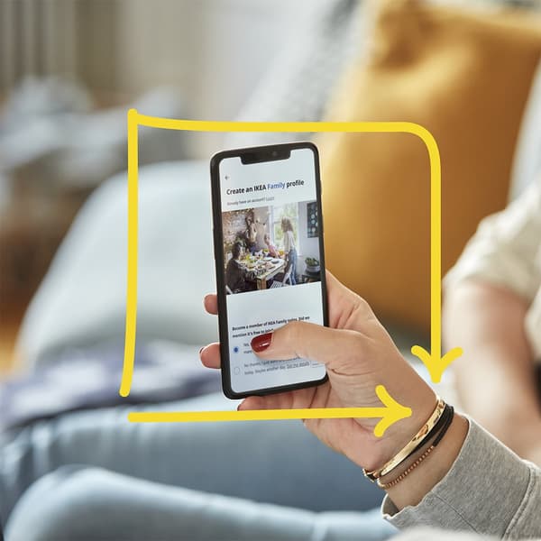 Eine Person hält ein Handy in der Hand auf dem die IKEA Family Seite zu sehen ist.