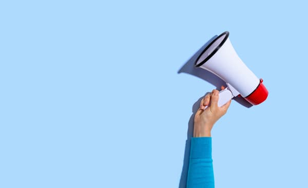 Eine Person hält ein weißes Megaphone in die Luft.