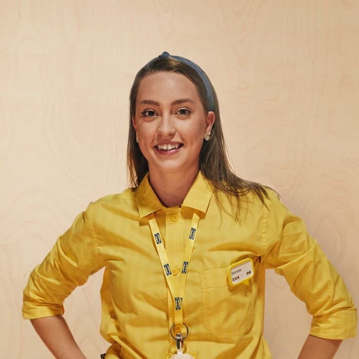 Eine Person in IKEA Mitarbeiterkleidung lächelt.