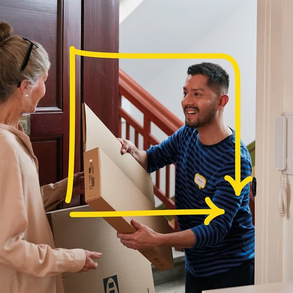 Eine Person öffnet die Tür und nimmt von einem Lieferanten ein Paket entgegen.