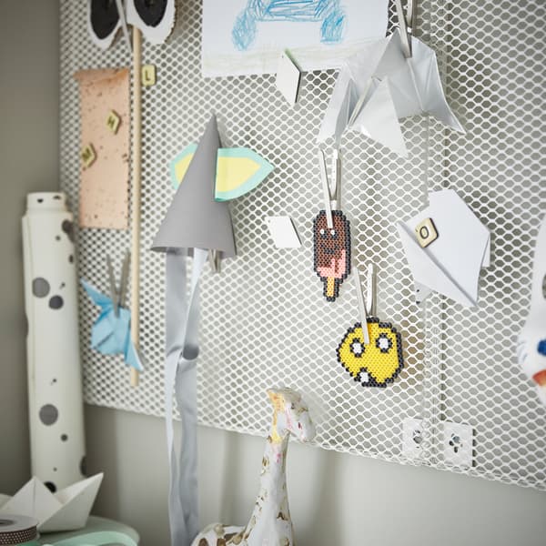 Eine weiße SÖDERGARN Notiztafel mit Magneten an einer grünen Wand, versehen mit Basteleien von Kindern