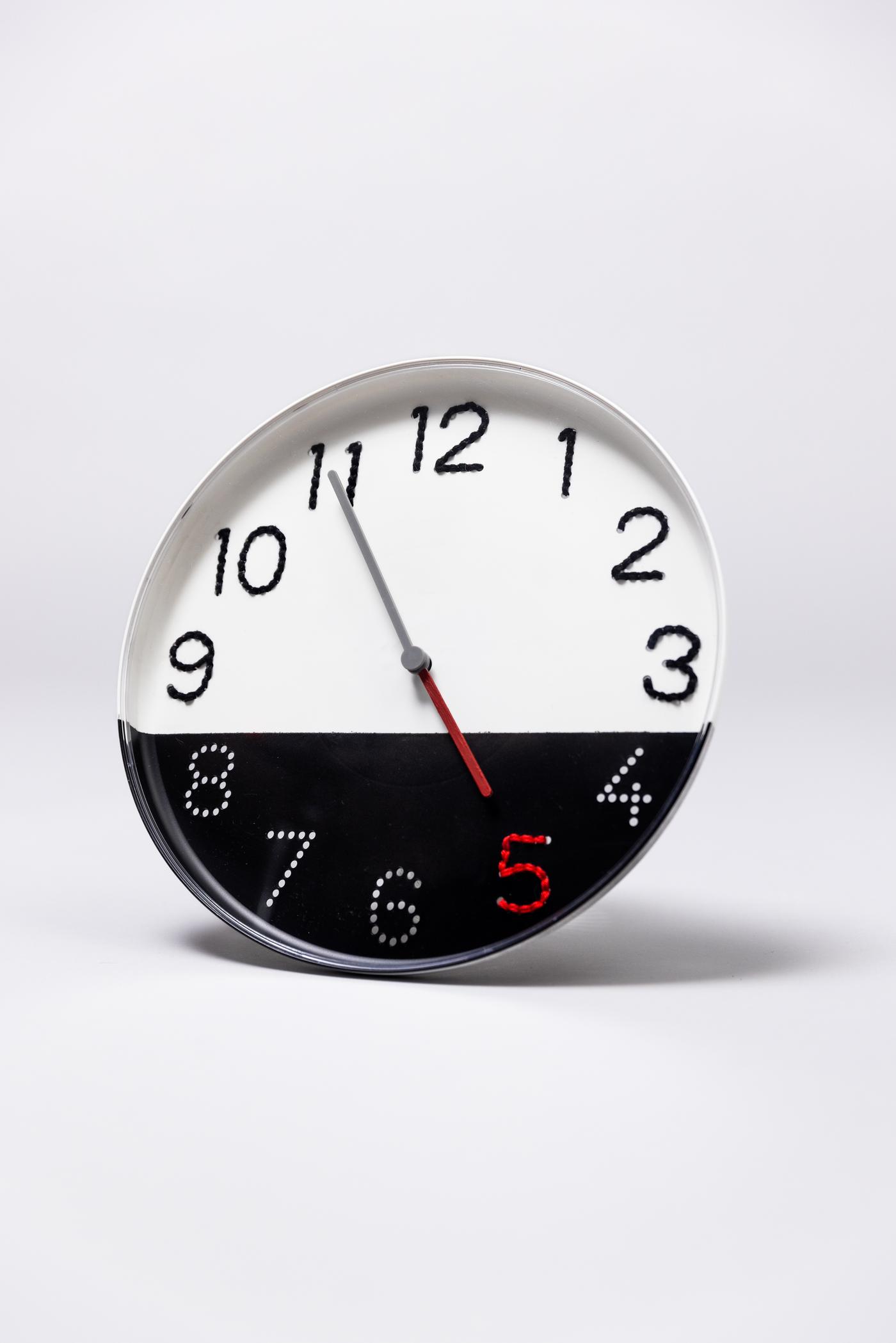 Eine weiße Uhr die auf der unteren hälfte schwarz ist liegt auf einem weißen Hintergrund.