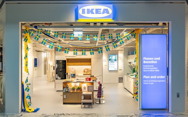 Eingang des IKEA Planungsstudios in St.Pölten, geschmückt mit kleinen schwedischen Flaggen. Im Inneren ist eine moderne Kücheninsel zu sehen.
