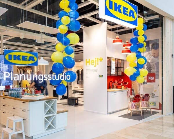 Eingangsbereich eines IKEA Planungsstudios mit gelb-blauer Ballondekoration, Küchenausstellung und Beratungstresen – kompakte Lösung für individuelle Wohnplanung auf kleiner Fläche.

