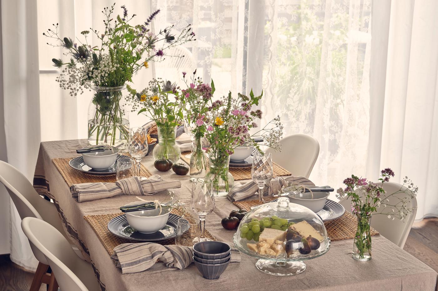 Elegant dining table with floral centrepiece and natural light, with striped napkins, plates, bowls and glassware.