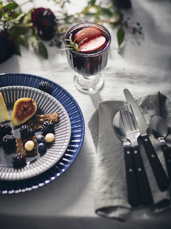 Elegant table setting including a white tablecloth, a light dish on a STRIMMIG side plact, and a drink in a VARDAGEN goblet.