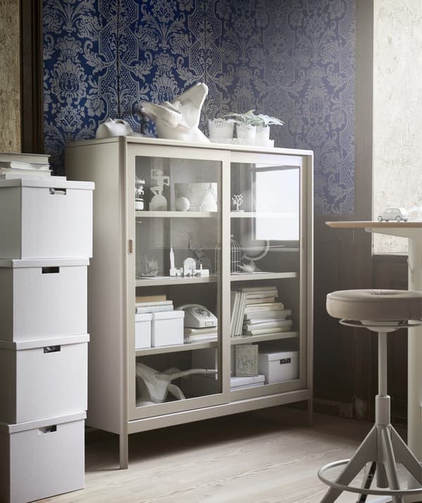 Élément beige à portes vitrées dans le coin d'un bureau décoré de papier peint bleu à motifs.