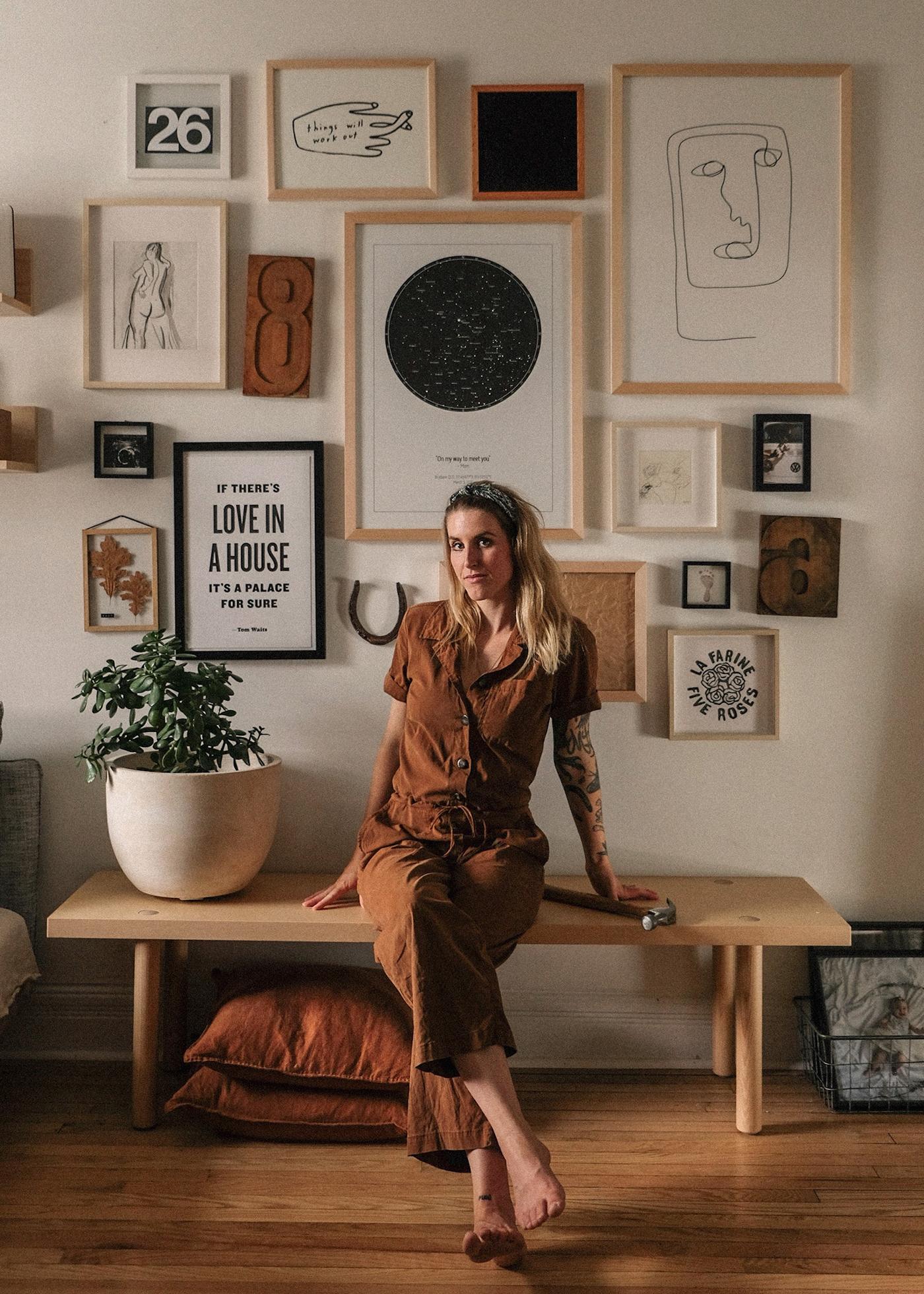 Emilie, la créatrice de contenu et styliste, assise sur un banc devant un mur de galerie dans son appartement.