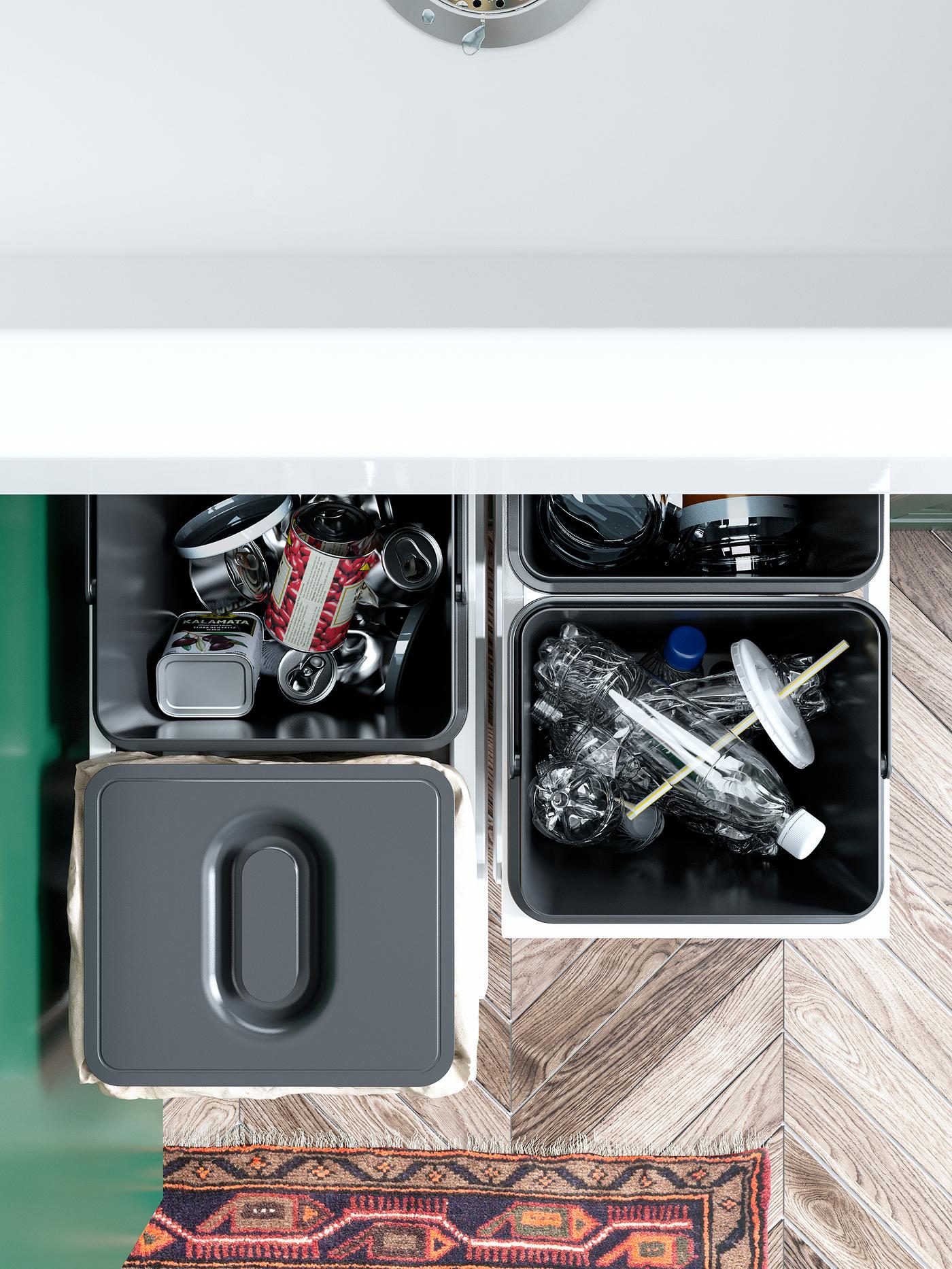 Empat tong pengasingan sampah VARIERA IKEA berwarna hitam berisi botol plastik dan tin kosong. Salah satu tong mempunyai penutup di atasnya.