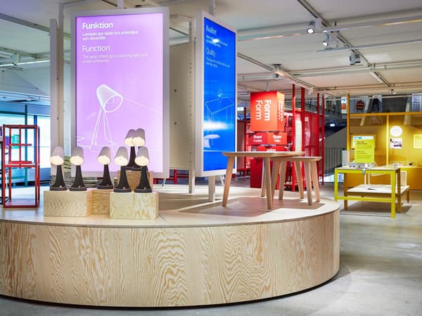 En bild som är tagen i IKEA Museumet i Älmhult som visar en läslampa framför en demokratisk design uppställning.
