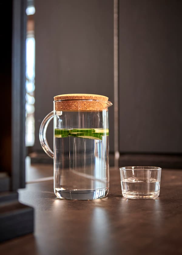 En detaljbild på en bringare med vatten och ett glas bredvid. 