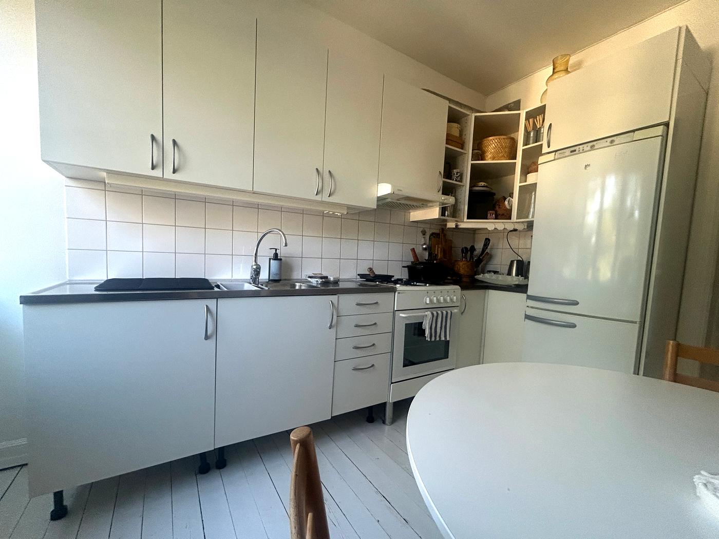 En före-bild på ett ljust kök med underskåp och överskåp. Till höger i bild syns en ugn och ett kyl/frysskåp.
