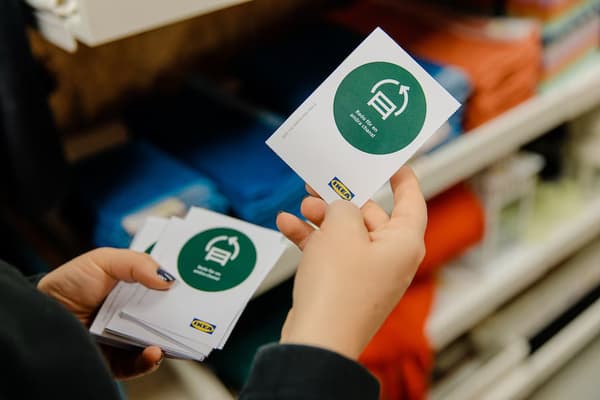 En individ som håller i en IKEA etikett som handlar om hållbarhet.