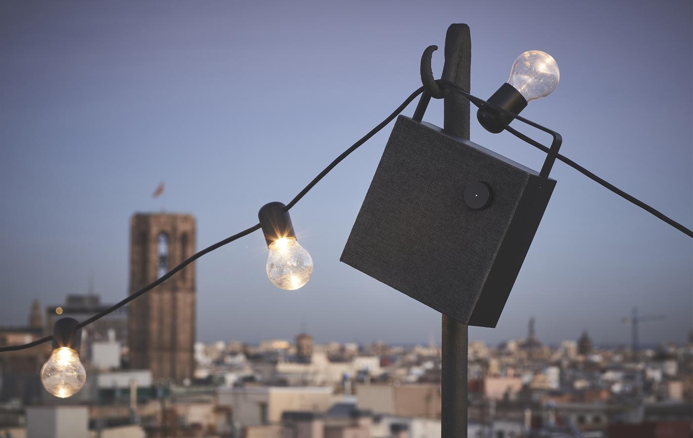Enceinte noire et guirlande lumineuse accrochées dehors.