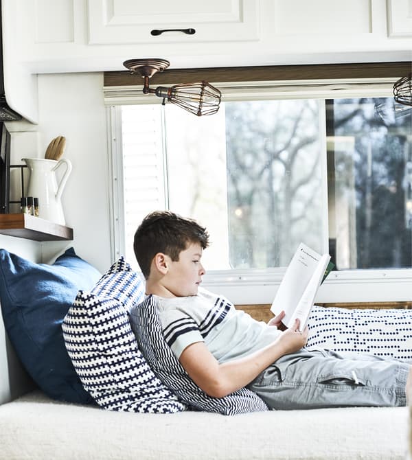 Enfant en train de lire un livre sur un divan.