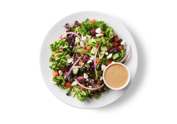 Ensalada griega, servida sobre una mezcla de verduras con queso feta y vinagreta griega