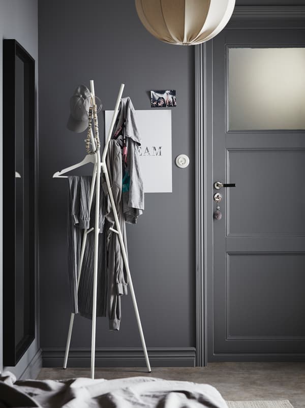 Entrée dans les tons de gris. Près de la porte d’entrée se trouve un portemanteau EKRAR où sont accrochés divers vêtements.