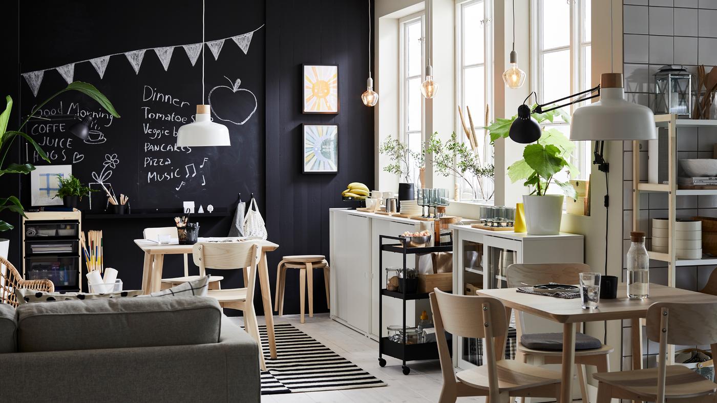Es ist ein Esszimmer mit drei grossen Fenstern und einer Wand zu sehen, die mit Kreidetafel gestrichen ist. Ausserdem befinden sich hier zwei LISABO Tische in Eschenfurnier mit passenden Stühlen.