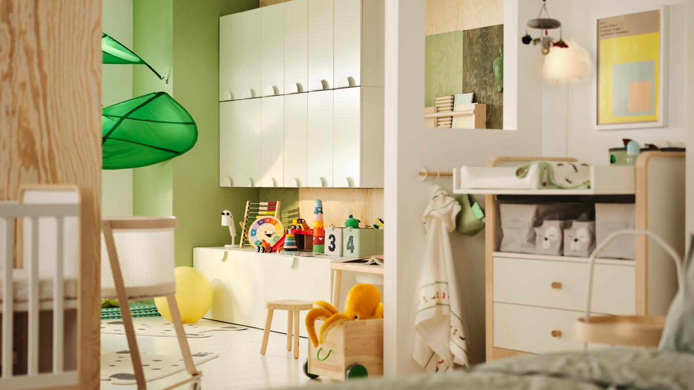 Es ist ein Kinderzimmer zu sehen, das zum Teil durch eine Wand geteilt wird. Auf einer Seite stehen SMÅSTAD Schränke mit Spielzeug. Auf der anderen befindet sich ein Wickelbereich.