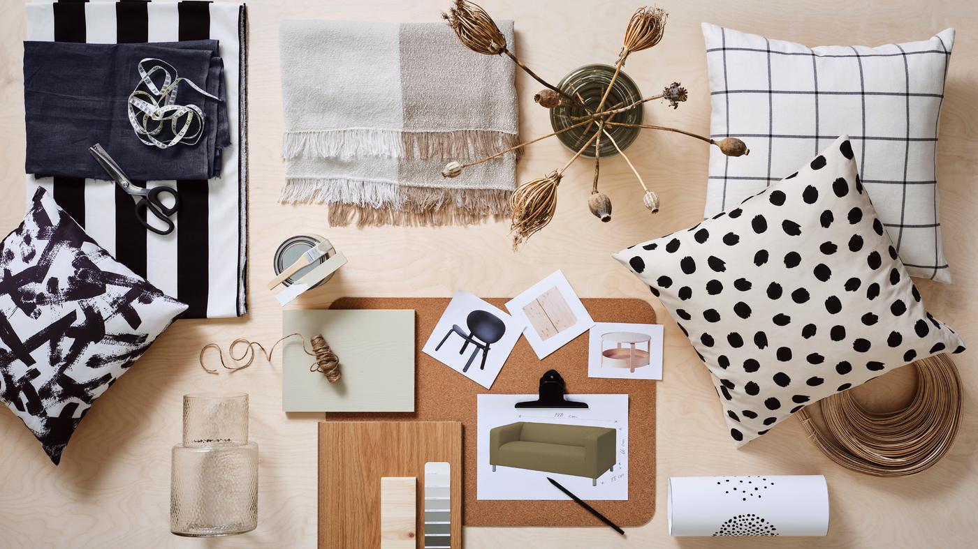 Es ist ein Moodboard zu sehen, auf dem Bilder von Möbeln liegen. Daneben befinden sich Kissen, zwei KONSTFULL Vasen aus Glas, Meterware und weitere Materialmuster.