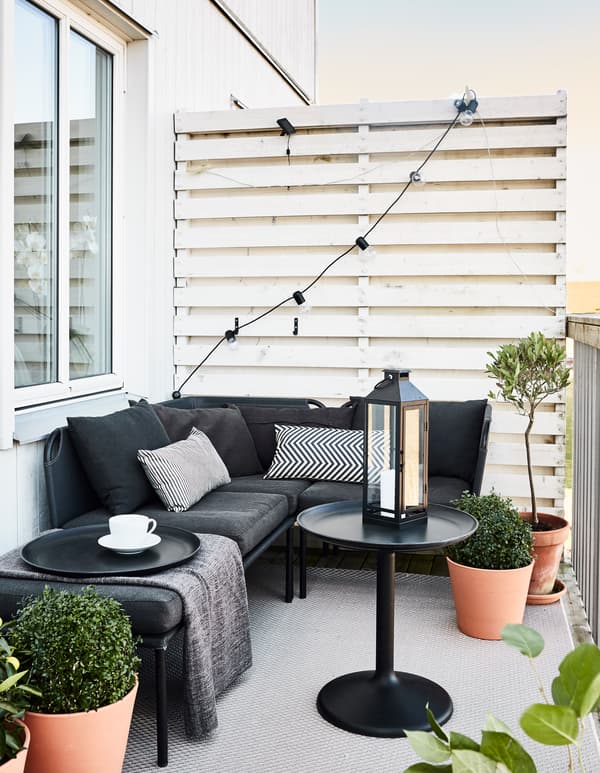 Espace extérieur meublé avec des meubles de couleur neutre, dont un canapé, une table basse et un tapis.