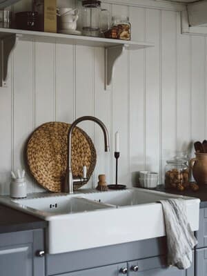 Et køkken i traditionel stil beklædt med hvide træpaneler i et sommerhus.