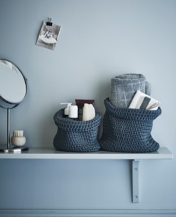 Étagère de salle de bain avec nécessaire de toilette et serviettes dans des paniers en textile