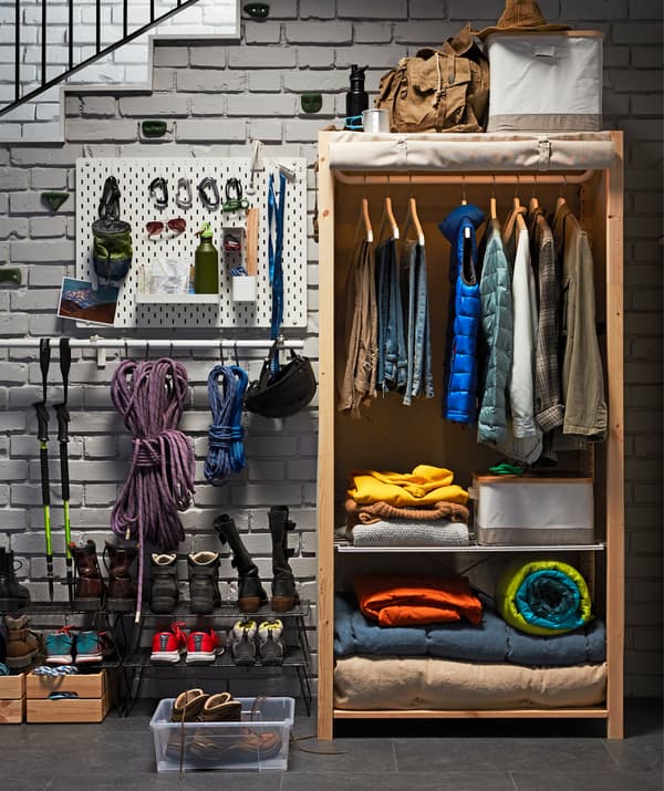 Étagère IKEA IVAR en pin massif avec housse à enrouler, remplie de vêtements sur cintre et de couvertures.