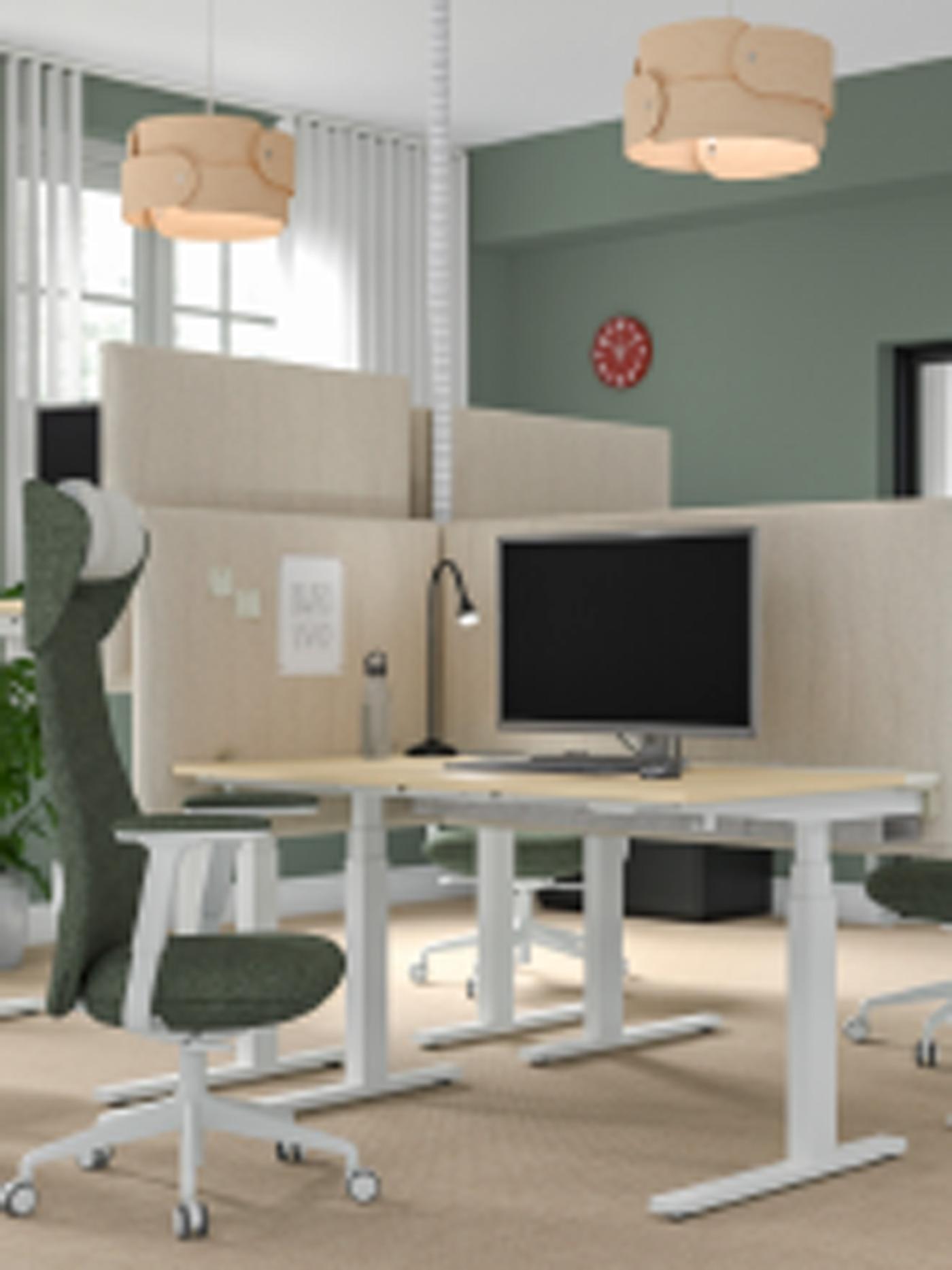 Ett modernt kontor med gröna väggar och en arbetsstation med skrivbordsavdelare och en avskärmning på ett MITTZON skrivbord.