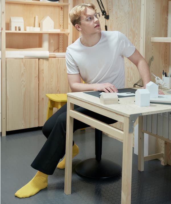 Étudiant en pleine réflexion assis à un bureau et travaillant à un projet.