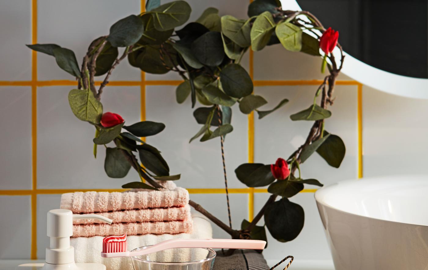 Eucalyptus green IKEA SMYCKA artificial leaf branches shaped like a heart, decorating a bathroom shelf.