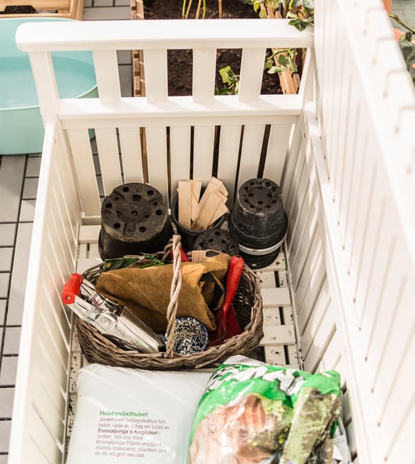 Extra pots, tools and soil are stored in a white storage bench.