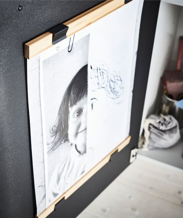 Face intérieure d’une porte d’armoire de cuisine, avec deux supports de poster – en haut et en bas – qui encadrent l’œuvre d’un jeune artiste.