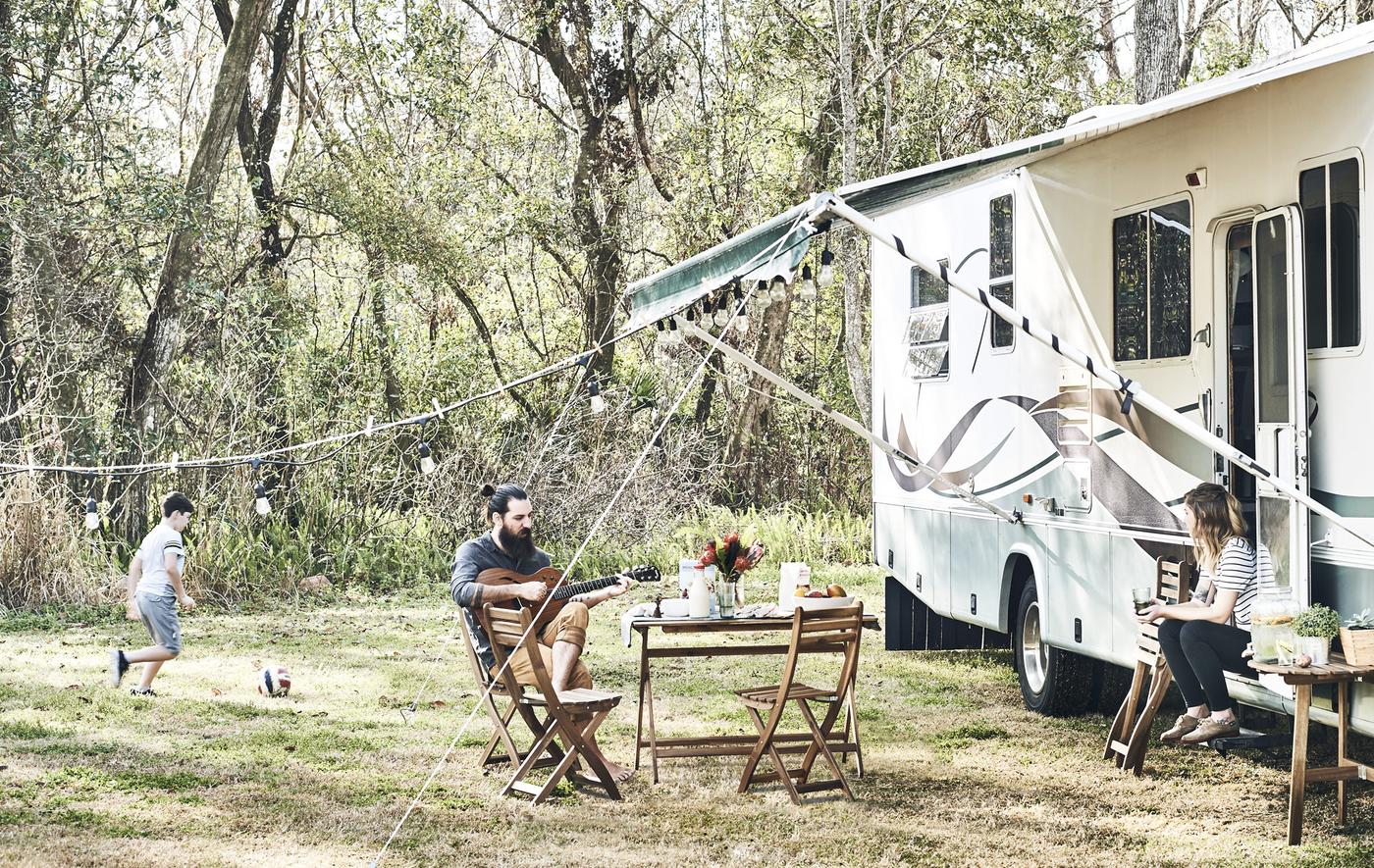 Famille en train de se détendre devant un mobil home à la campagne.