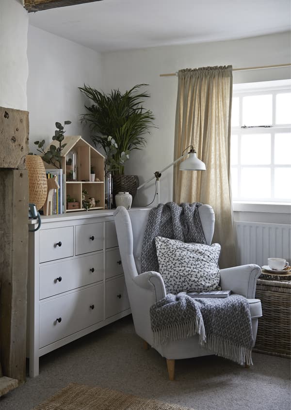 Fauteuil avec plaid, coussin et lampe.