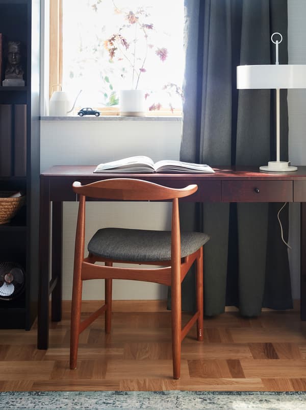 Fauteuil DANSKE en chêne et son assise en tissu conçu pour IKEA dans les années 60 placé devant un bureau en bois foncé.