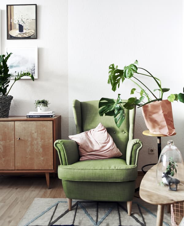 Fauteuil vert à côté d’une table d’appoint et d’une plante en pot.