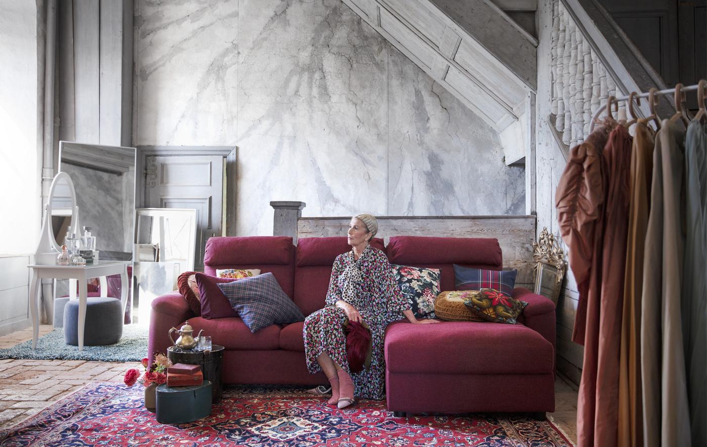 Femme assise sur un canapé modulaire dans une pièce aux murs revêtus de marbre.