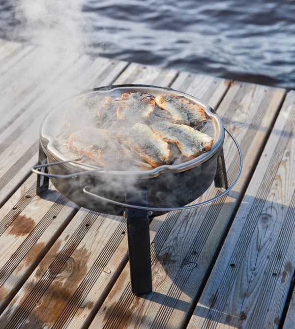 Filets de hareng grillés sur un petit barbecue posé sur le ponton.