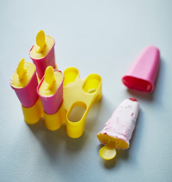 Filled ice pop moulds and a frozen yogurt pop sit on a counter.