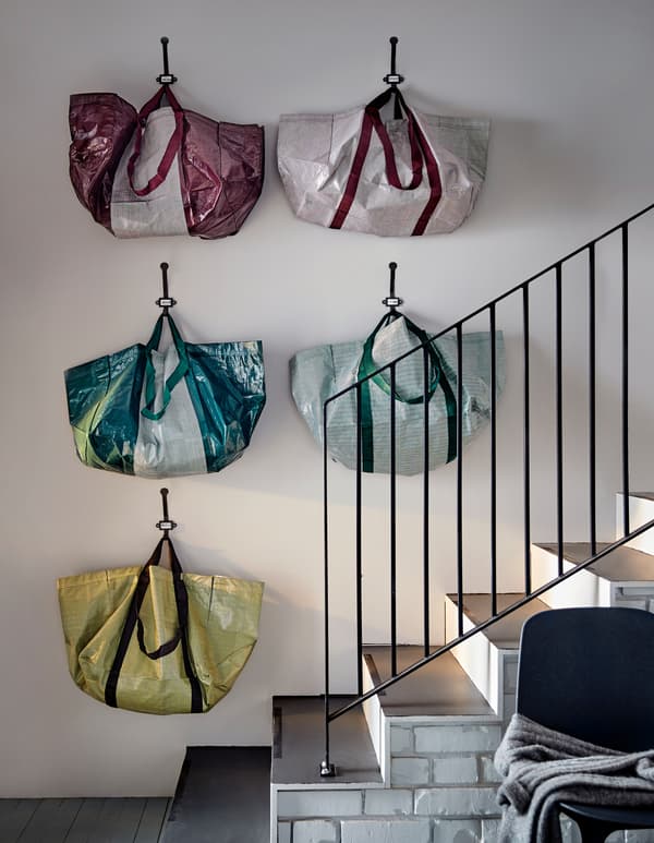 Five multi-coloured storage bags arranged on a wall near a staircase.
