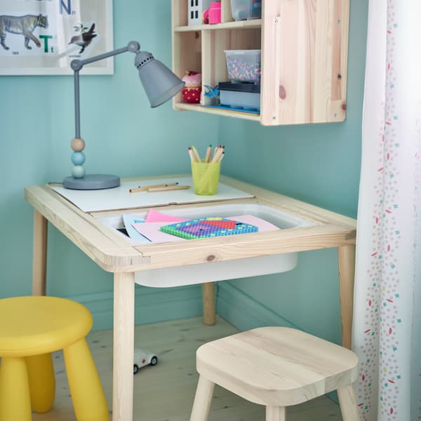 FLISAT pine table for children with white plastic bins underneath.