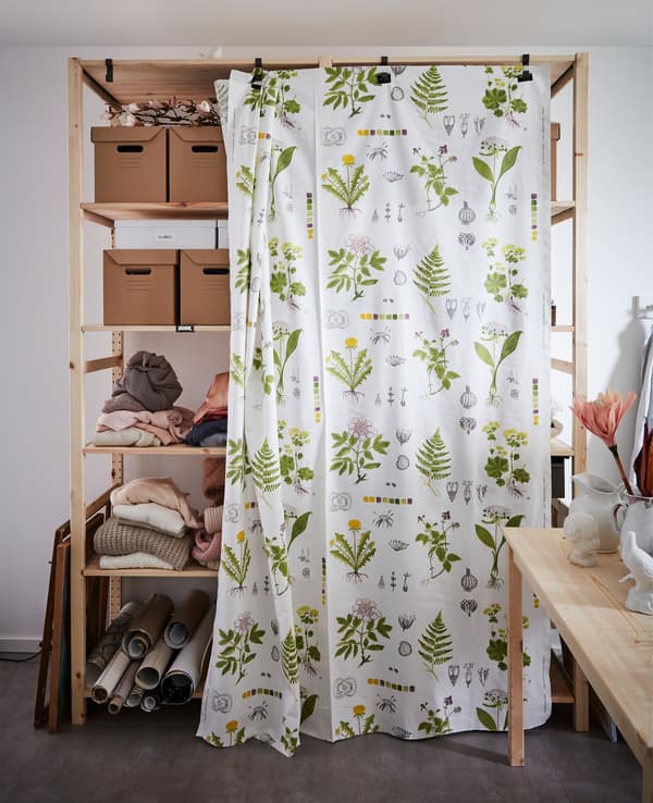 Floral-patterned DORTHY metre fabric hooked onto shelves to make a style statement and hide boxes and clothes.