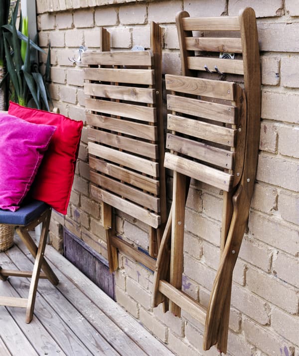 Foldable wooden chairs hanging on a brick wall.