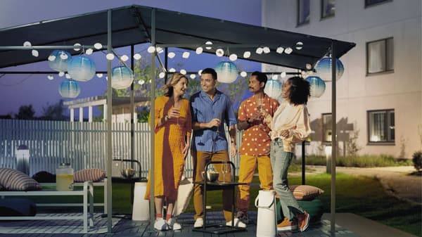 Four friends gathered outside under a lit canopy
